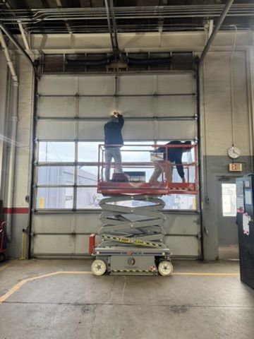 Technicians on a scissor lift at a windowed sectional door