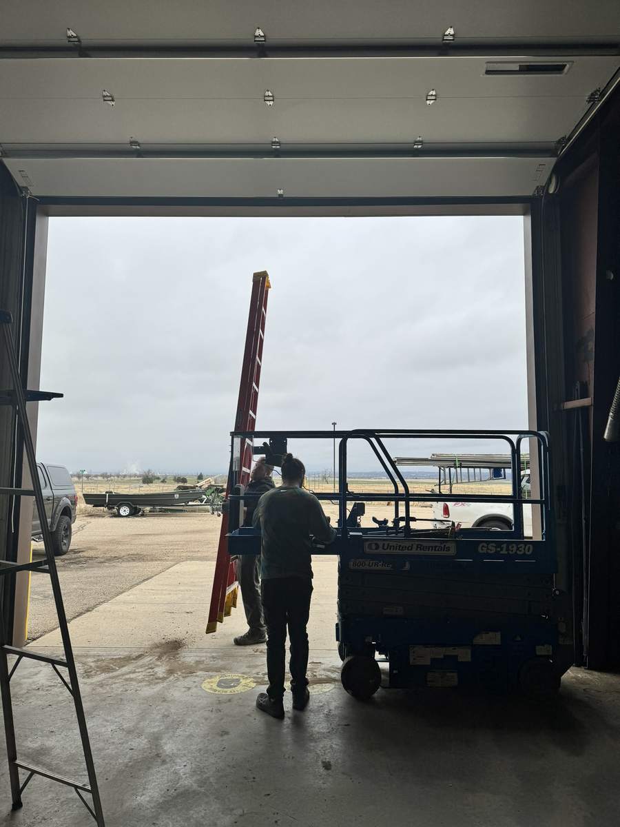 Crew with a scissor lift inside a large open sectional door